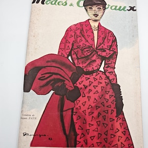 Peut inclure: Couverture de magazine de mode vintage avec une femme en robe rouge à motifs triangulaires noirs. Le titre "Modes & Travaux" est en noir et vert. Le texte est en français.