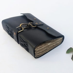 May include: A black leather journal with a clasp closure. The journal has a flap that secures with a metal clasp. The edges of the journal are stitched with a woven design. The pages are aged.