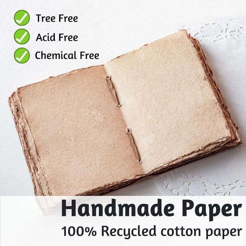 May include: Open handmade paper journal with a natural, textured appearance. The pages are held together with a simple binding. The text on the image reads "Tree Free", "Acid Free", "Chemical Free", "Handmade Paper", and "100% Recycled cotton paper".