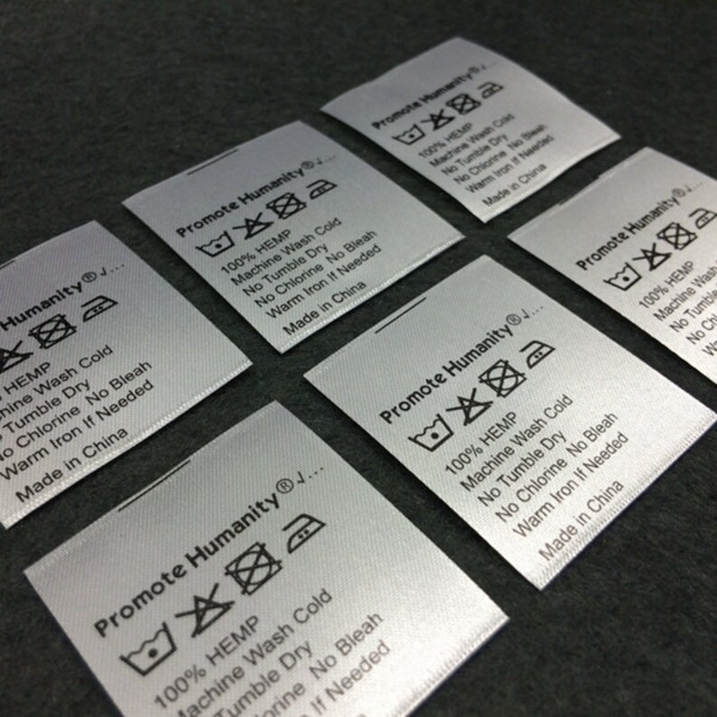 May include: Five white satin labels with black text and symbols. Each label reads "Promote Humanity" and includes care instructions for 100% hemp fabric. The instructions include machine wash cold, no tumble dry, no chlorine bleach, warm iron if needed, and made in China.