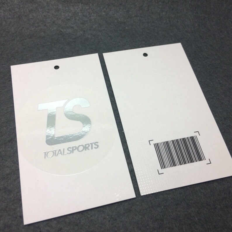 Pode incluir: Duas etiquetas de pendurar brancas com um logotipo circular prateado que diz "TS TOTALSPORTS" de um lado e um c&oacute;digo de barras do outro.