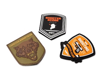 Könnte beinhalten: Drei gestickte Patches aus schwarzem, orangem und grünem Stoff. Der erste Patch ist schwarz mit weißem Text, der "Shooter Score 2023" lautet, und einer weißen Umrandung von Südkorea. Der zweite Patch ist grün mit einer braunen Wolfs-Illustration und dem Text "Lausitzer Airsoftklub". Der dritte Patch ist orange mit schwarzem Text, der "Shooting 2023" und "Shooter Score" lautet, und einer schwarzen Illustration einer Pistole.