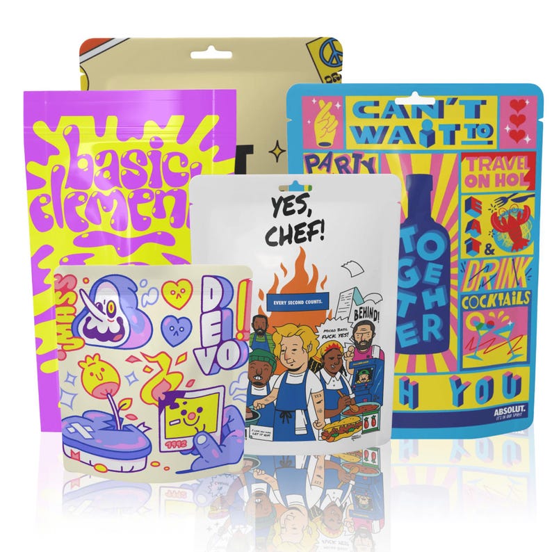 Peut inclure: Plusieurs pochettes color&eacute;es et &agrave; motifs avec divers motifs et textes. L'une affiche "basic element" en jaune et violet. Une autre dit "YES, CHEF!" avec une illustration de chef. D'autres pochettes affichent des phrases comme "CAN'T WAIT TO PARTY" et "TOGETHER".