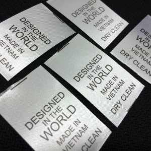 May include: Close-up of several white satin labels with black text that reads "Designed in the World, Made in Vietnam, Dry Clean".
