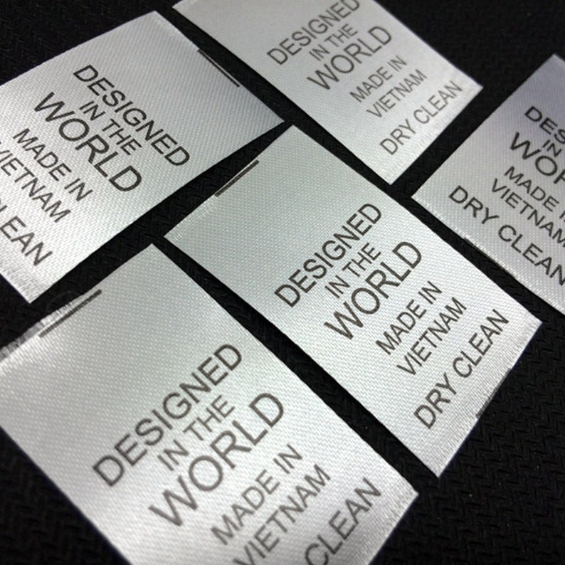May include: Close-up of several white satin labels with black text that reads "Designed in the World, Made in Vietnam, Dry Clean".