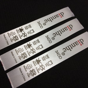May include: Three white satin garment care labels with black and red text. The labels are for a bra size 34DD and the brand name "dianthe". The labels include instructions for washing, drying, ironing, and bleaching.