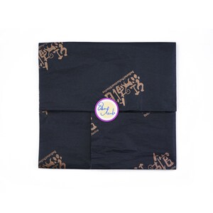 May include: Black tissue paper with a gold design featuring the text "Dedicated Professional Printers" and a purple circle sticker with the text "Don't  Judge" in blue.