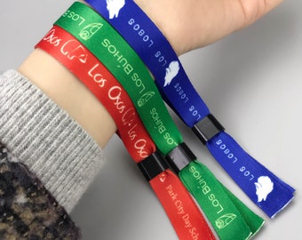 May include: Four colorful wristbands with different animal logos and text. The wristbands are red, green, blue, and green. The text on the wristbands reads "Los Osas", "Los Buhos", "Los Lobos", and "Park City Day School".