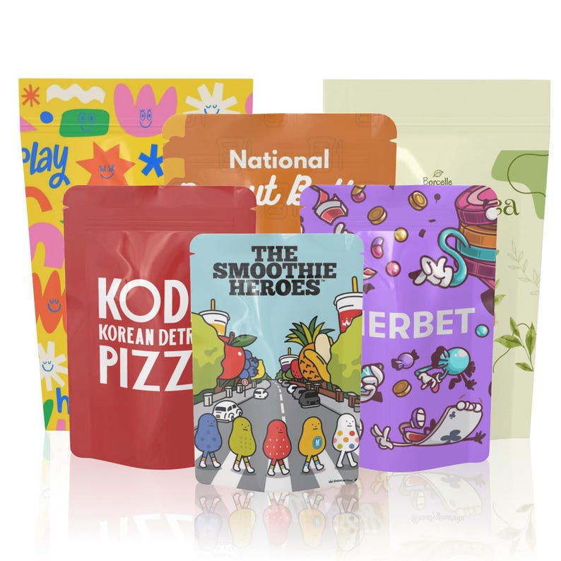 Peut inclure: Plusieurs pochettes color&eacute;es avec des motifs et du texte vari&eacute;s. Les pochettes pr&eacute;sentent des illustrations et des textes tels que "play", "KOD Korean Detr Pizza" et "The Smoothie Heroes". Les pochettes sont dans des tons de jaune, rouge, orange, violet et vert.