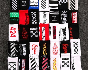 May include: A collection of various crew socks in black, white, red, and blue. The socks feature stripes, graphic text, and designs, including the words "Respect", "Thrasher", and "Fuck You Pay".