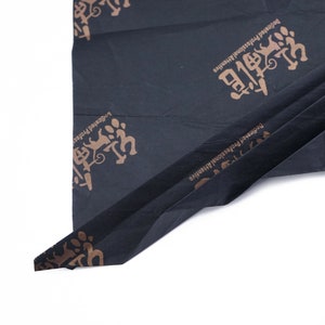 May include: Black tissue paper with a gold print of the text "Dedicated Professional Initiative" and a stylized image of a cat.