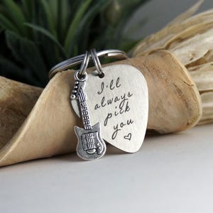May include: Silver guitar pick keychain with the inscription "I'll always pick you" and a small silver guitar charm.