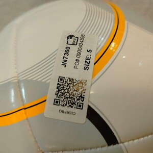 Puede incluir: Un bal&oacute;n de f&uacute;tbol blanco y gris con detalles en negro y amarillo. Una etiqueta adjunta con el texto "JN7360", "TALLA: 5" y un c&oacute;digo QR. El bal&oacute;n est&aacute; dise&ntilde;ado para deportes y recreaci&oacute;n.
