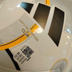 Puede incluir: Bal&oacute;n de f&uacute;tbol blanco y gris con el logotipo negro de Adidas y detalles amarillos. El bal&oacute;n tiene el texto "MATCH BALL REPLICA CLUB" y una pegatina con c&oacute;digo QR. Dise&ntilde;ado para el juego de clubes.