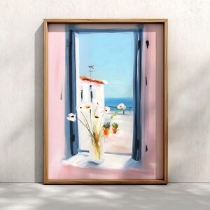 May include: A framed wall art print depicting an open window with dark blue shutters and pink walls. A glass vase containing white flowers sits on the windowsill. Through the window, a white building, a blue sea, and a clear sky are visible.