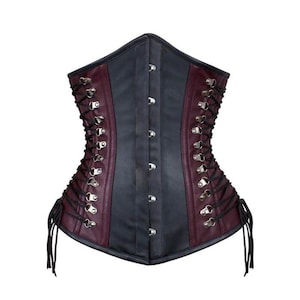 May include: A two-tone corset in black and burgundy. The corset features a central panel of black material, flanked by burgundy panels. It has silver-toned eyelets and a lace-up back. The front has silver-toned clasps.