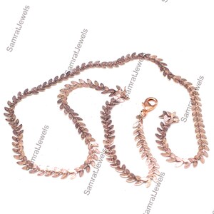 May include: A rose gold necklace with a leaf pattern. The necklace has a lobster clasp and is made up of small, detailed leaf shapes. The jewellery is shown against a white background.