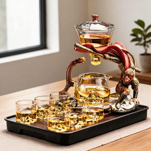 May include: A tea set featuring a glass teapot and six small glass cups with mountain-shaped bases. The set includes a decorative stand depicting a figure in armour with a red cape, holding a glass infuser above the teapot on a black tray.