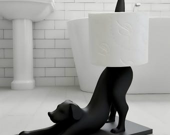 May include: A matte black dog-shaped toilet paper holder in a stretching pose. The dog's hindquarters support a vertical rod holding a roll of white toilet paper with a subtle embossed leaf pattern. The entire structure sits on a rectangular base.