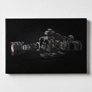 May include: An exploded view of a black digital camera showing its internal components, including the lens elements, sensor, circuit boards, and outer casing, all suspended in a disassembled arrangement against a solid black background.