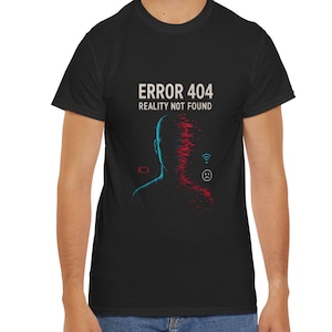 Può includere: T-shirt nero con la scritta "ERROR 404 REALITY NOT FOUND" sopra una grafica blu e rossa di una silhouette umana. La grafica include una batteria, Wi-Fi e un'icona utente.