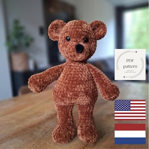 Op de afbeelding: Een handgemaakte bruine teddybeer met een zwarte neus en kleine zwarte ogen. De beer is gemaakt van een zacht, getextureerd materiaal. Een wit vierkant met de tekst "PDF pattern" staat in de rechterbovenhoek. De Amerikaanse en Nederlandse vlaggen staan rechtsonder.