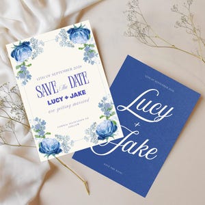 Puede incluir: Dos tarjetas de invitación de boda. Una es de color crema con detalles florales azules y el texto "Save the Date" con los nombres "Lucy + Jake". La otra es azul con los nombres "Lucy + Jake".