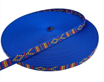 May include: A roll of vibrant blue webbing with a decorative patterned edge. The pattern features a repeating design of orange, yellow, and red geometric shapes. This durable webbing is suitable for various crafting and sewing projects.