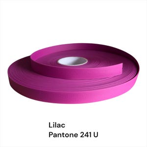 Puede incluir: Un rollo de cinta de color lila, Pantone 241 U, se muestra sobre un fondo blanco. La cinta est&aacute; enrollada firmemente, revelando un n&uacute;cleo de cart&oacute;n blanco. El texto "Lilac" y "Pantone 241 U" est&aacute;n impresos debajo.