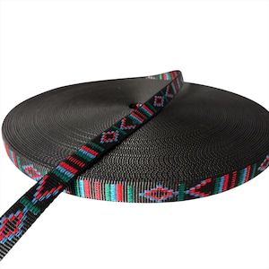 May include: A roll of black webbing with a decorative patterned strap. The strap has a repeating design in red, blue, and green. The webbing is tightly wound, forming a circular shape.