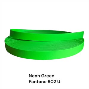 Puede incluir: Un rollo enrollado de material verde ne&oacute;n, posiblemente una correa o cinta. El material tiene una superficie texturizada y es de un color vibrante y llamativo. El texto "Neon Green Pantone 802 U" se muestra debajo.