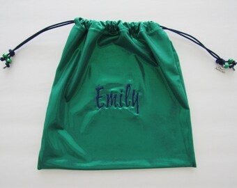 May include: A green drawstring bag with a metallic sheen. The bag has a navy blue drawstring and a navy blue embroidered name "Emily".