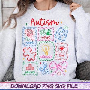 May include: A light gray sweatshirt with the word "Autism" in red script. The sweatshirt features colorful framed illustrations with words like "accept," "adapt," and "love." The bottom of the image has the text "DOWNLOAD PNG SVG FILE."