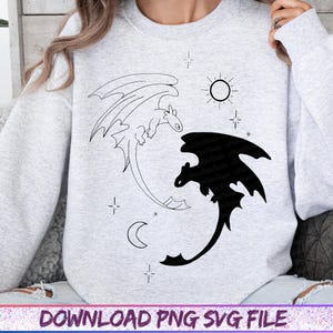 May include: Light gray sweatshirt featuring a black and white dragon design. The design includes two dragons, a sun, a moon, and stars. The text "DOWNLOAD PNG SVG FILE" is at the bottom of the image.
