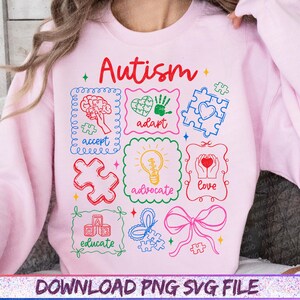 May include: A light pink sweatshirt with the word "Autism" in red script. The design includes colorful puzzle pieces, a brain, a heart, a handprint, a lightbulb, and the words "accept", "adapt", "advocate", "love", and "educate".