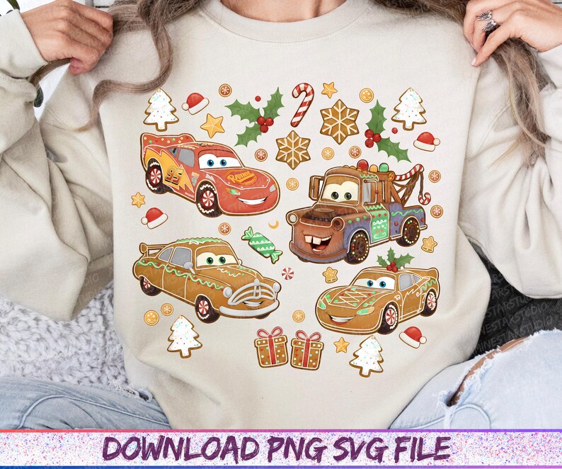 May include: A beige sweatshirt featuring a festive design with cartoon cars decorated as gingerbread and Christmas elements. The design includes red, brown, and green cars, gingerbread cookies, candy canes, and holly.