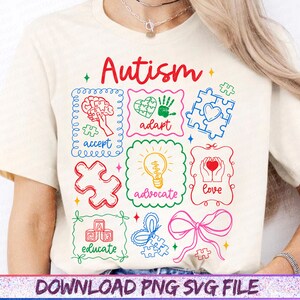 May include: Cream-colored t-shirt with a colorful graphic design featuring the word "Autism" in red script. The design includes puzzle pieces, a brain, a heart, and the words "accept," "adapt," "advocate," "love," and "educate."