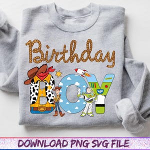 May include: A light gray sweatshirt featuring the word "Birthday" in brown rope-style lettering. The word "BOY" is designed with cartoon characters and imagery from the movie Toy Story. The sweatshirt has long sleeves.