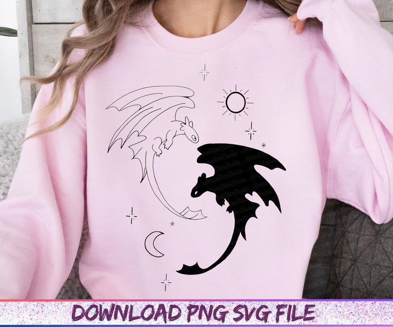 May include: A light pink sweatshirt featuring a black and white dragon design. One dragon is a black silhouette, the other is an outline. The design includes a sun, moon, and stars. The text "DOWNLOAD PNG SVG FILE" is at the bottom.