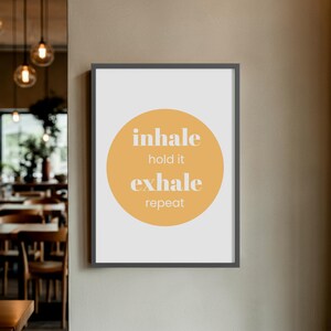 Peut inclure: Une affiche encadr&eacute;e avec les mots "inhale, hold it, exhale, repeat" en blanc. Le texte est centr&eacute; sur un cercle jaune sur fond blanc. Le cadre est gris fonc&eacute;.