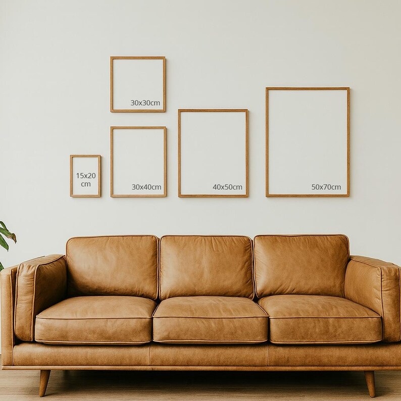 K&ouml;nnte beinhalten: Eine Sammlung gerahmter Kunstdrucke in verschiedenen Gr&ouml;&szlig;en, darunter 15x20 cm, 30x30 cm, 30x40 cm, 40x50 cm und 50x70 cm, die an einer wei&szlig;en Wand &uuml;ber einem braunen Ledersofa ausgestellt sind. Die Rahmen haben eine nat&uuml;rliche Holzoptik.