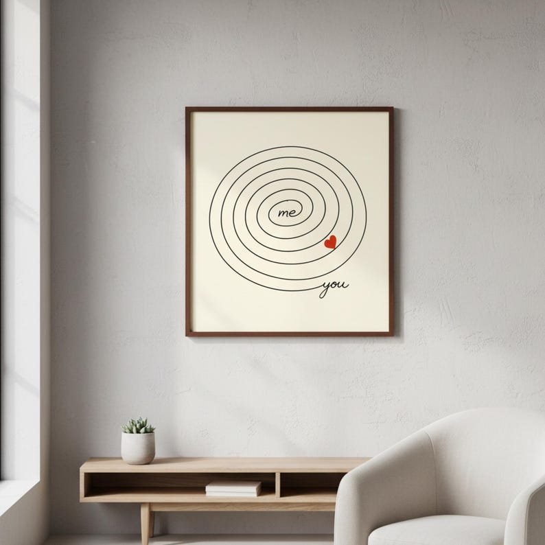 Op de afbeelding: Een ingelijste print met een cr&egrave;mekleurige achtergrond toont een zwart spiraalontwerp. De woorden "me" en "you" zijn in zwarte letters geschreven, met een klein rood hart. De lijst is donkerbruin.