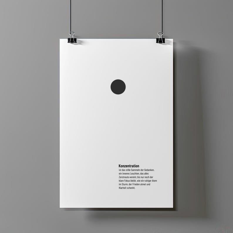 May include: A white poster with a black dot near the top centre, held by binder clips. The poster has German text at the bottom. The poster is hanging against a grey wall.