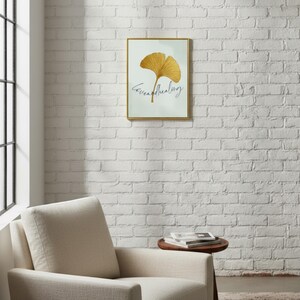 Pu&ograve; includere: Una stampa artistica incorniciata con un design a foglia di ginkgo dorata e la scritta "Serene Healing" in corsivo. L'opera d'arte &egrave; ambientata su uno sfondo chiaro e incorniciata in oro. La stampa &egrave; appesa a un muro di mattoni bianchi.