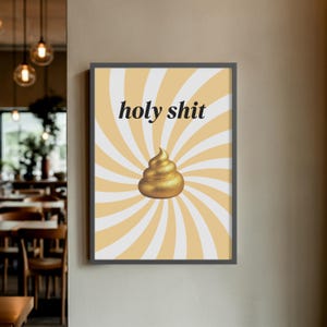K&ouml;nnte beinhalten: Gerahmter Kunstdruck mit den Worten "holy shit" in schwarzer Schrift &uuml;ber einem goldenen Kack-Wirbel auf gelbem und wei&szlig;em Hintergrund. Das Kunstwerk ist in einem dunkelgrauen Rahmen gerahmt.