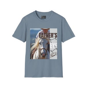 May include: A blue short-sleeve t-shirt featuring a graphic of a white horse with a rider, and the text "FATHER'S EYE" and "yee haw". The shirt has a small logo on the upper back.