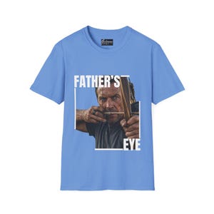 May include: Light blue t-shirt featuring a graphic of a man aiming a bow and arrow, with the text "FATHER'S EYE" in a white box. The shirt has a crew neck and short sleeves.