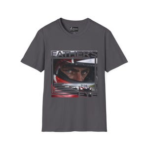 以下が含まれることがあります： レーシングドライバーのヘルメット内の目元を捉えた「FATHER'S EYE」の文字がプリントされたダークグレーのTシャツ。クルーネックと半袖で、カジュアルな装いに最適です。