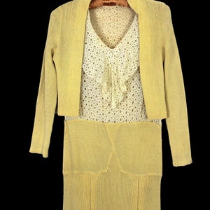 May include: A yellow knitted dress and matching cardigan set. The dress has a skirt with a slight A-line shape and a lace top with a ruffled neckline.