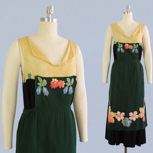 May include: A sleeveless dress with a green skirt and a yellow bodice. The bodice has a black panel with embroidered flowers in shades of blue, pink, and green. The skirt has a band of embroidered flowers around the hem.